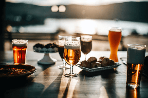 Five craft beers on a table with containers of nuts