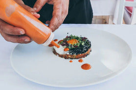 a chef adding fruit sauce to a savory dish